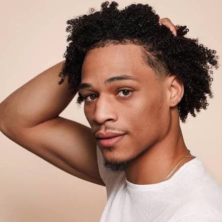 Shahid Hinton with a hand in his hair, smiling at the camera