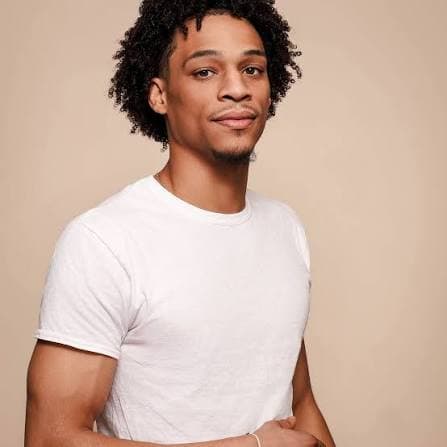 Shahid standing with his arms folded, in a white t-shirt